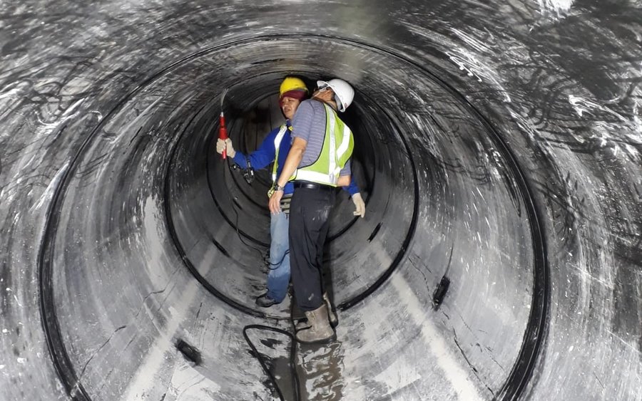 Stormwater technicians carrying out a spark test on an HDPE lining inside a large diameter pipe